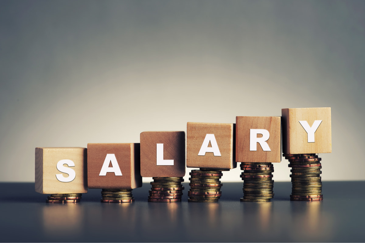 Blocks stacked on money spelling out salary, to demonstrate a gross income salary calculator